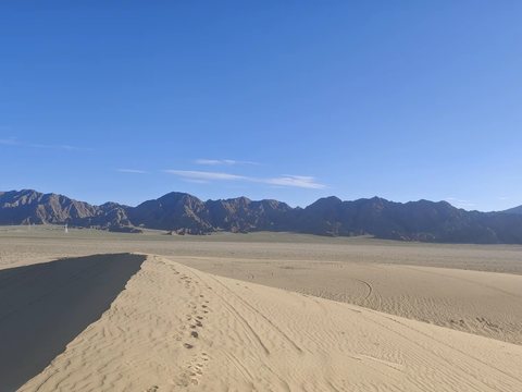 A sand dune ridge and a range of bare dark mountains
