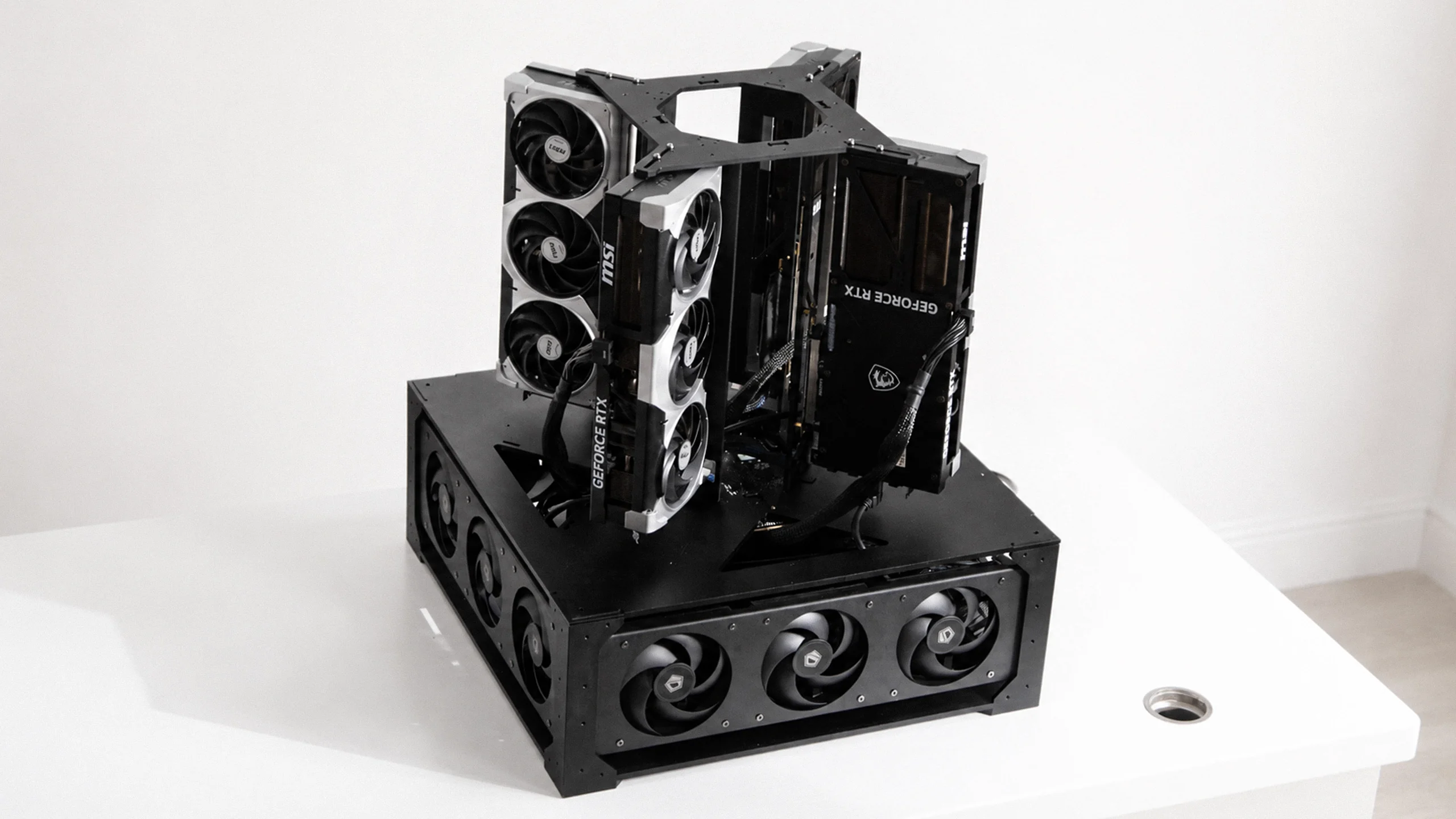 The 4× 5090 build — four RTX 5090s stacked in the open cube frame over the fan base