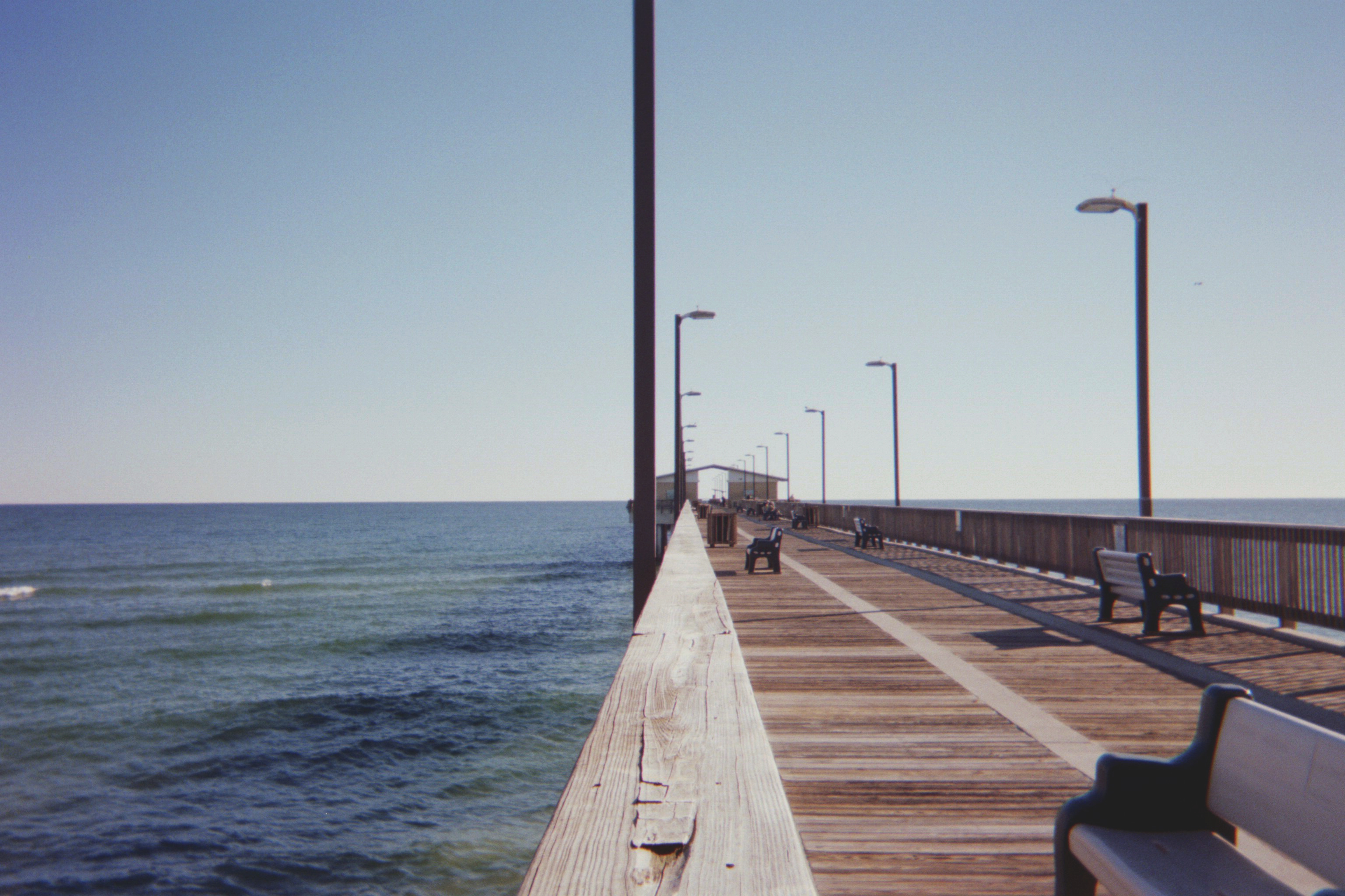 a_wooden_walkway_with_benches_and_a_body_of_water