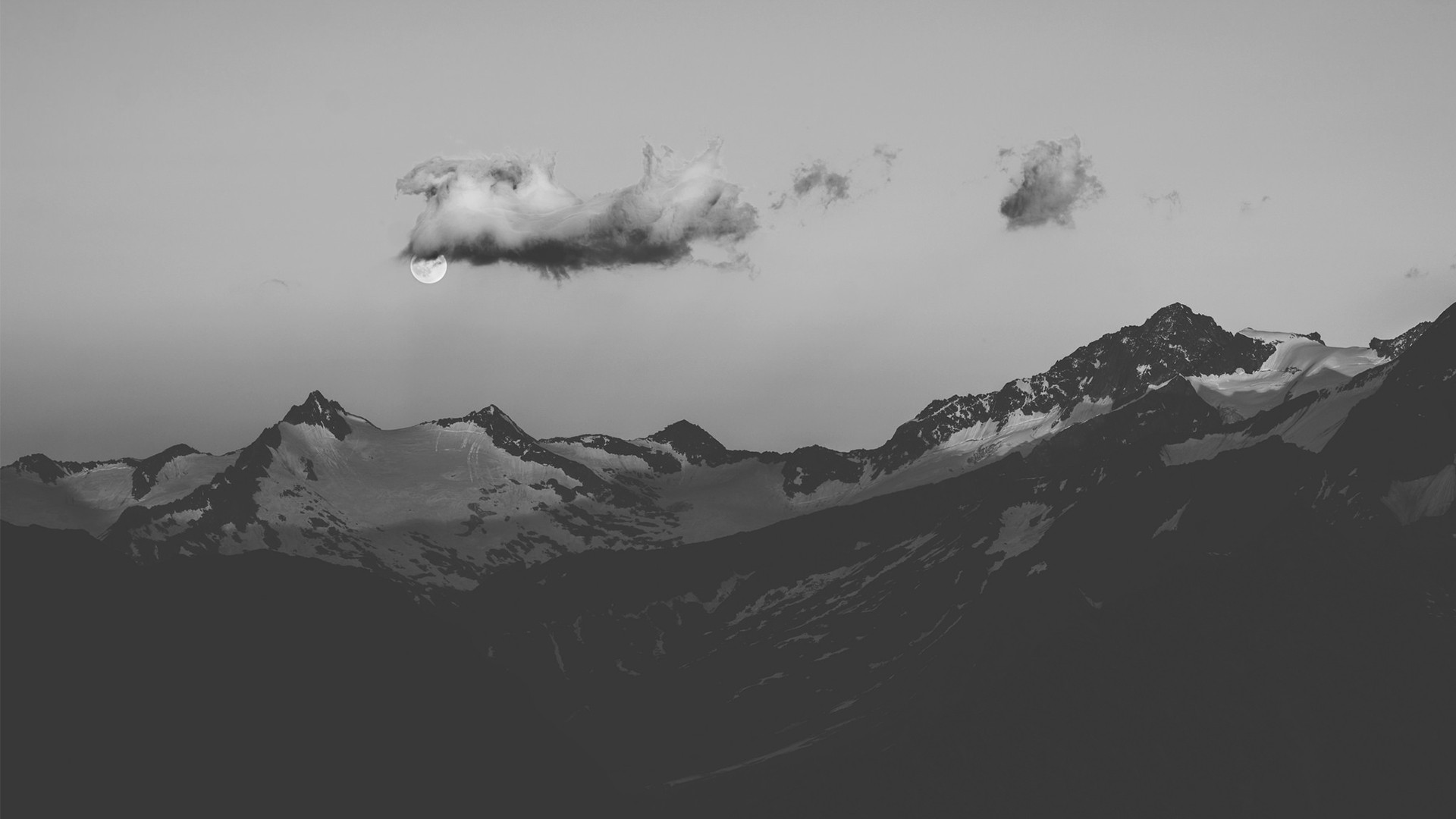 a moon in the sky above mountains